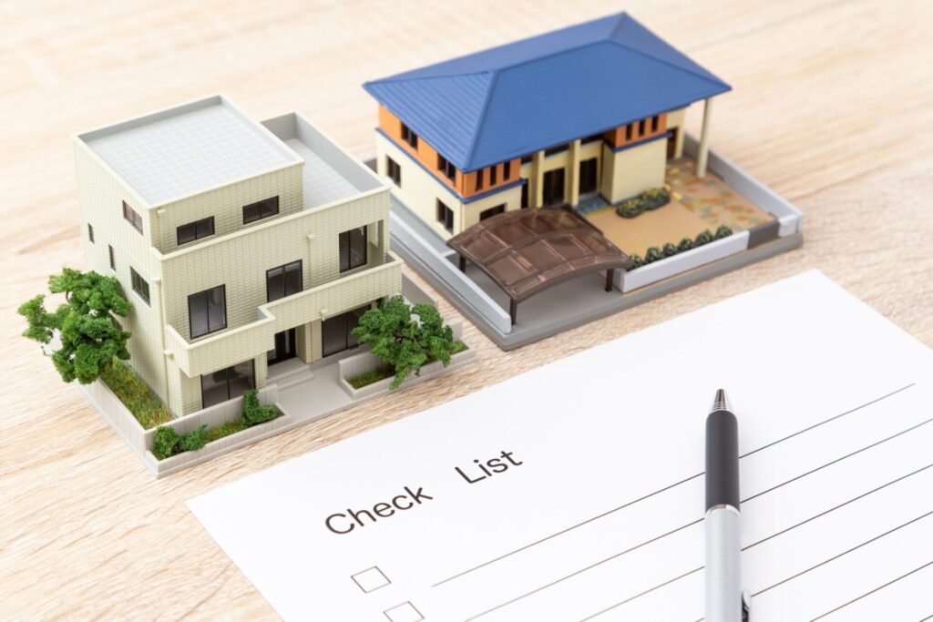 机に置かれた住宅模型とチェックリスト