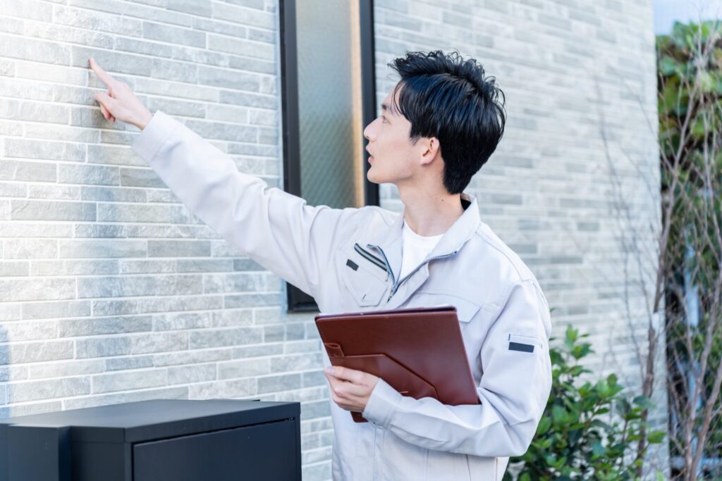 家の外壁を点検する住宅専門スタッフ